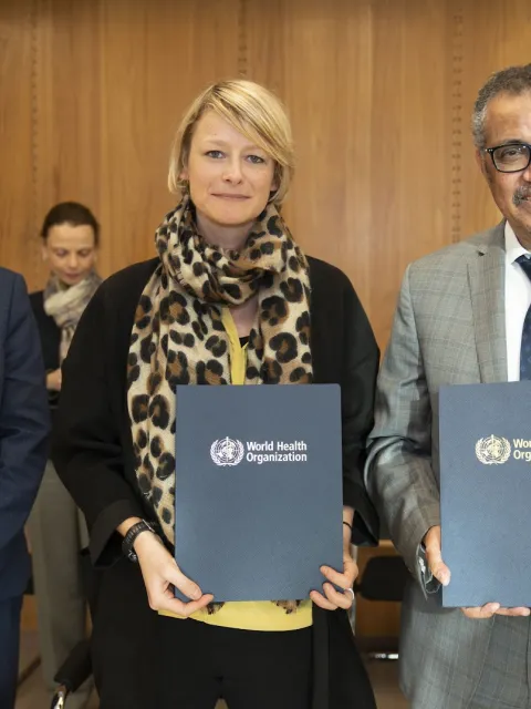 Cary Adams, CEO of UICC, with Katie Dain, CEO of NCDA and Dr TedrTedros Adhanom Ghebreyesus, Director-General of WHO, holding up the MoU formalising relations between NCDA and WHO in 2020