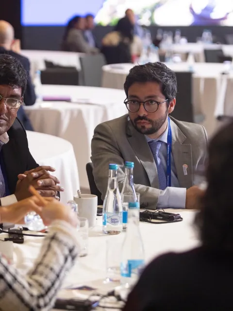 Four UICC Young Leaders, two women, two men, discussing at a round table during UICC World Cancer Leaders' Summit in Kazakhstan, 2019