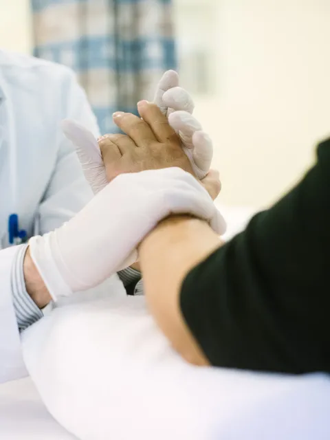 Male doctor wearing sterilised gloves holding the hand of a Caucasian woman patient