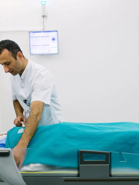 Male patient being placed by male caregiver on a scanning bed at Acibadem Kozyatağı Hospital, Turkey