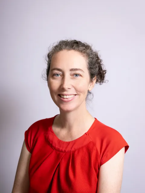 Headshot of Caucasian woman, Kate Simms, Associate Professor at the University of Sydney, wearing a red top