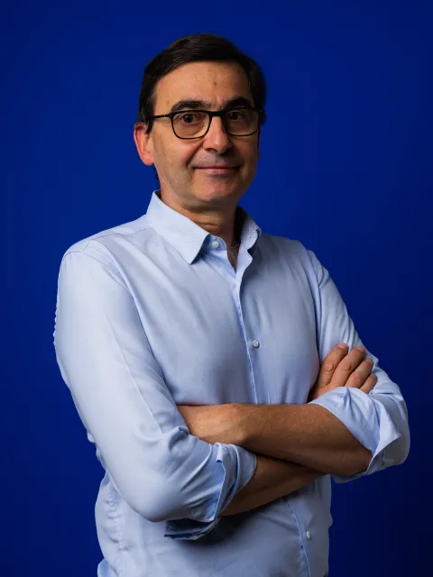 Headshot of Caucasian man in blue shirt with arms crossed