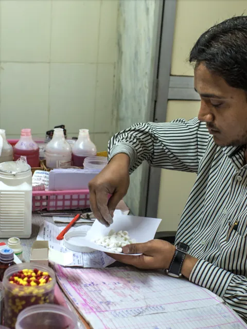 Man sitting at a desk weighing out medication