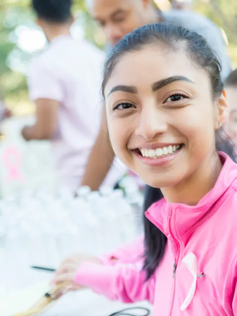 Young Southeast Asian woman wearing a pink top smiles to the camera