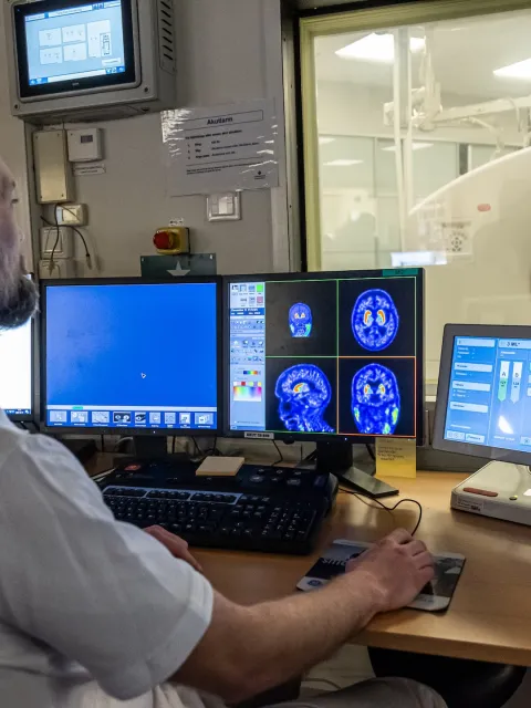 Middle age white male in white shirt looking at cancer screening images on computer screens