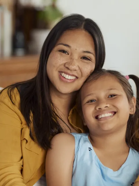 Mother with daughter sitting on a couch smiling