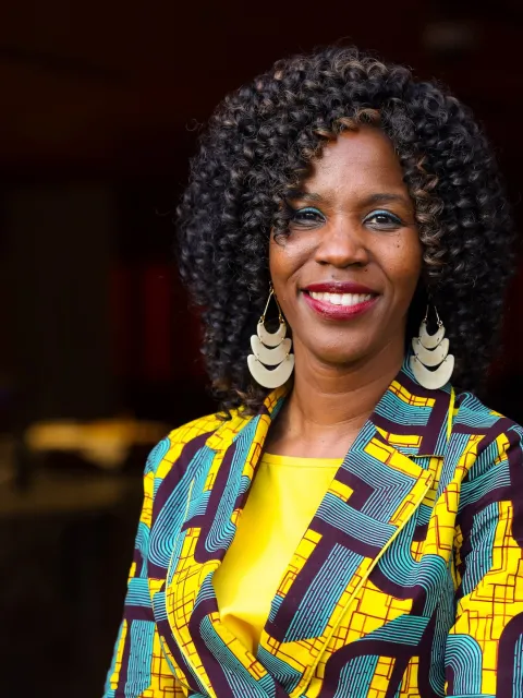 Dr Miriam Mutebi, UICC Board Member, an African woman in green and yellow clothing