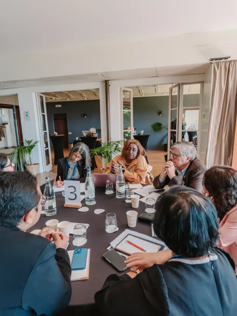 Diverse group of people at a professional seminar around a table, "Cancer Planners Forum" on a banner in the background