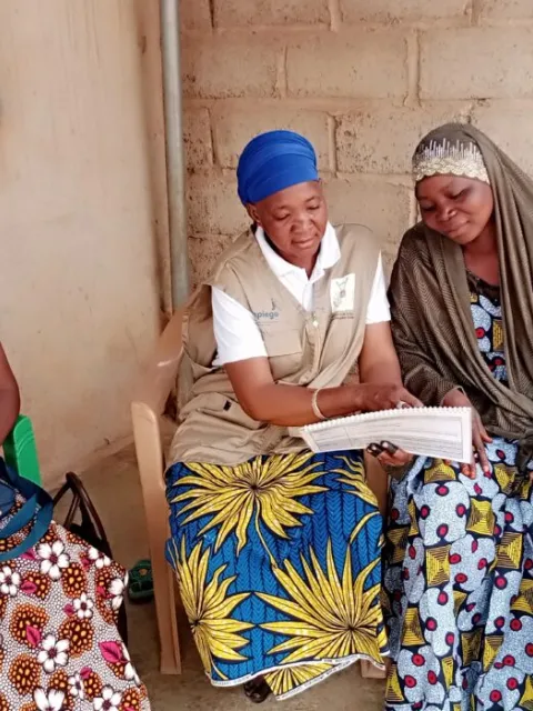 An African woman speaking to two others about health
