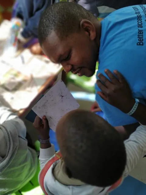 Black man in blue t-shirt engaging with children with cancer