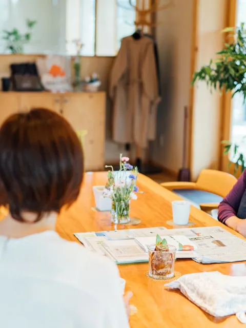 Three japanese women wearing masks sit at a table, with smiles