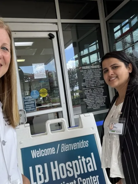 White woman in doctor's overalls with Asian woman with black sweater