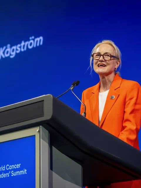 Ulrika Årehed Kågström, President of UICC, in orange suit against branded blue background
