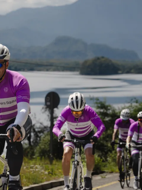 Cyclist uphill with lake and mountains in the background