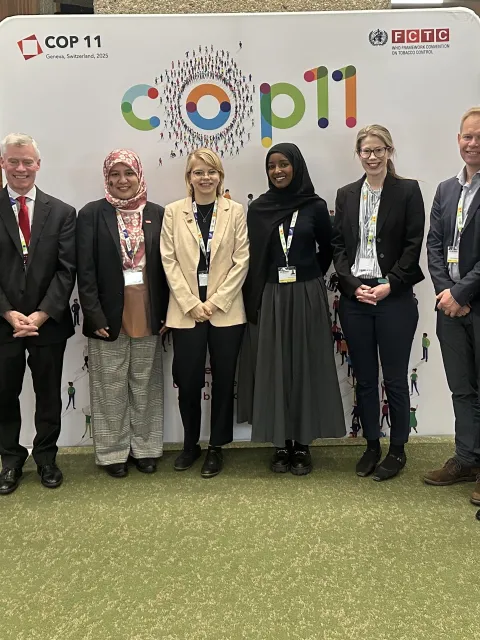 Diverse group of people posing in front of a branded COP11 backboard