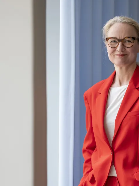2/3 body shot of middle-age white woman wearing red orange suit with white t-shirt