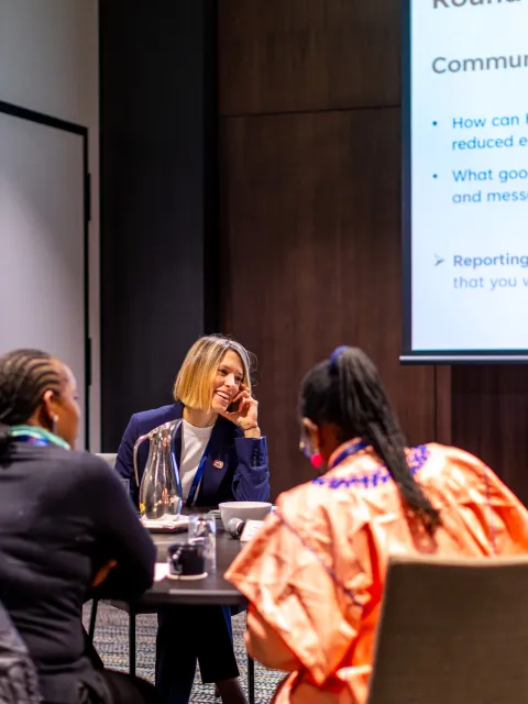 Six women of diverse ethnic and racial origins sitting around a roundtable in business setting