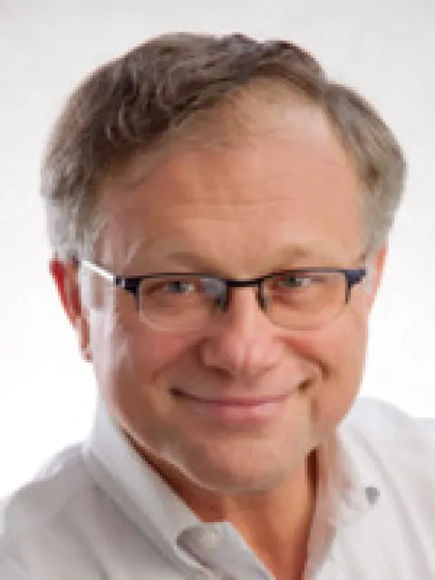 Headshot of middle-age Caucasian male smiling and wearing glasses in a white collar shirt