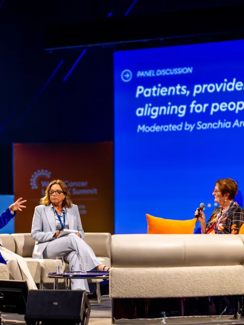 Three people on stage at a panel event on people-centred cancer care