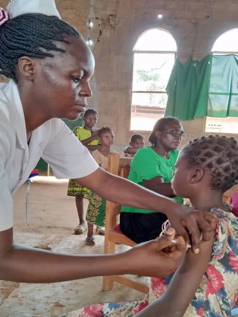 African nurse administering a vaccine to an African child