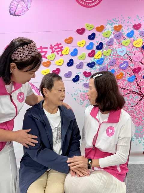 An elderly Asian cancer patient being comforted by two health workers