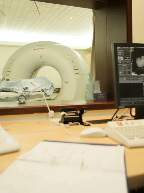 An African woman in lab coat checking scans as a patient goes through a scanning machine