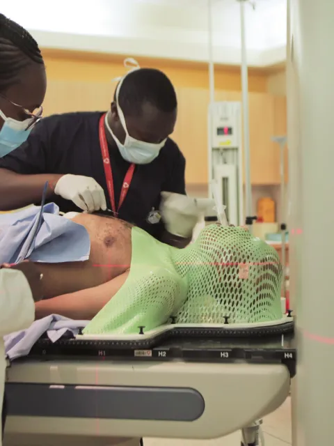 Male and female medical workers assisting a patient to lie down before entering a MRI scanning machine