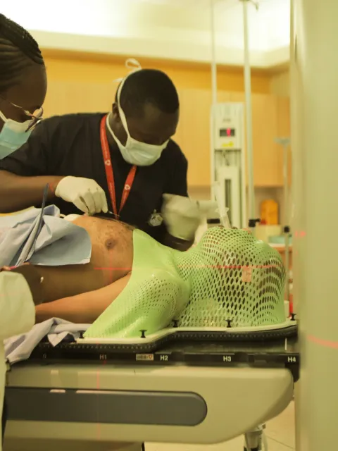 Male and female medical workers assisting a patient to lie down before entering a MRI scanning machine