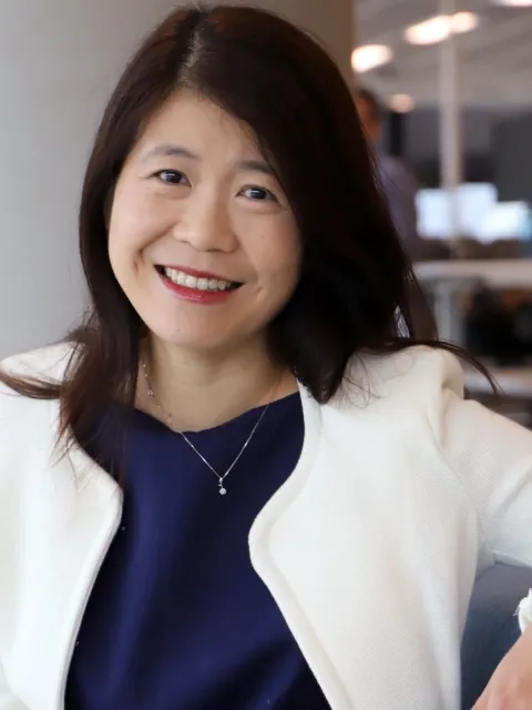 Headshot of an Asian woman, Charissa Feng, wearing dark shirt and white jacket