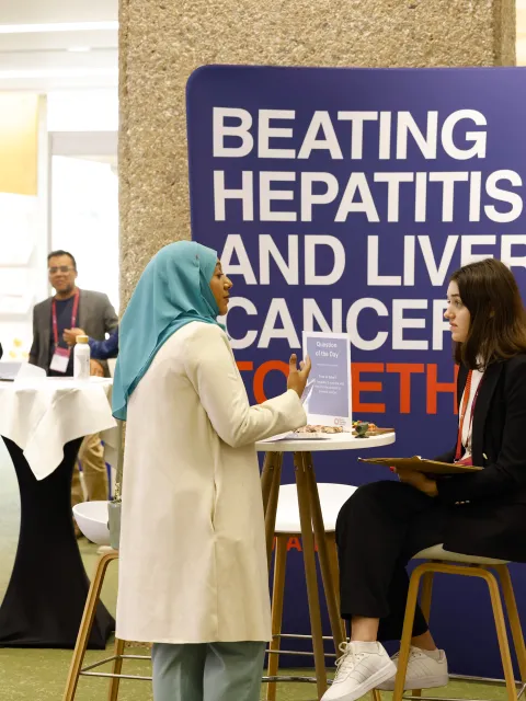 People at a conference, in front of a backdrop "Beating hepatitis and liver cancer"
