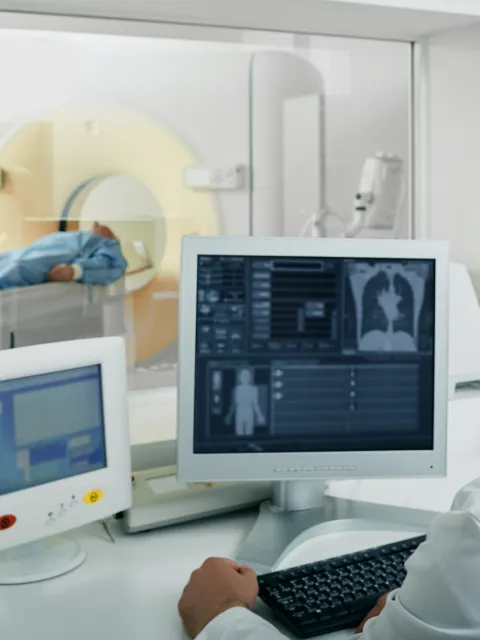 Doctor radiologist running CT scan for patient's body lungs from control room. Computed Tomography