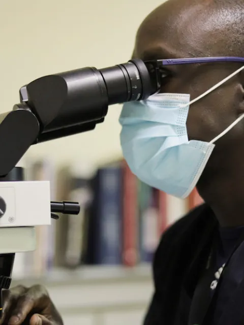 Man looking into a microscope, pathology unit at the Aga Khan University Hospital in Kenya