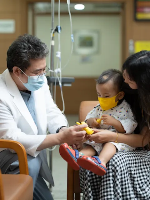 Doctor speaking to a woman and her child. (C) National Cancer Center - Korea (NCCK)