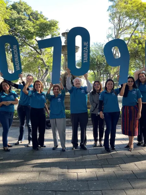 Staff of the Liga Nacional Contra el Cáncer Guatemala holding up number signs to spell out WHO's 2030 targets for cervical cancer elimination: 90, 70, 90