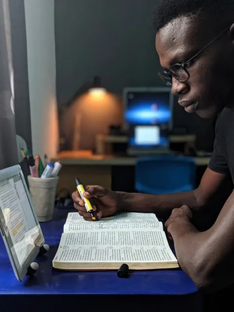 A man consulting a book and iPad, symbolising the value of online learning