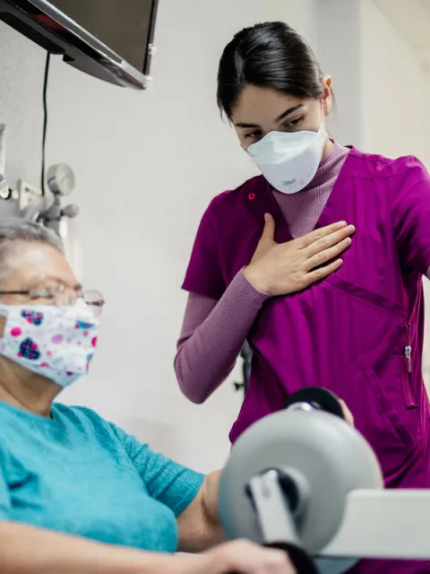 Older adult with cancer exercising on a stationary bike guided by a health worker at INCan, Mexico. Photo by Adán Jardón, (c) UICC.
