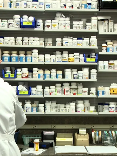 Pharmacist in front of medicine shelf