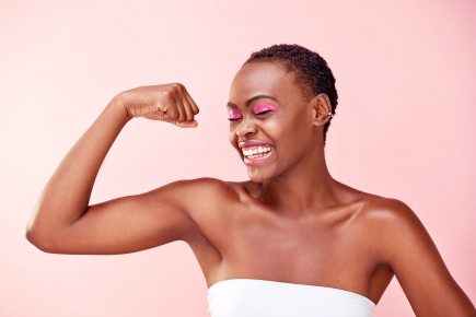 Black woman showing her muscles on pink background