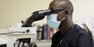 Man looking into a microscope, pathology unit at the Aga Khan University Hospital in Kenya