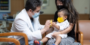 Doctor speaking to a mother holding a baby wearing masks 
