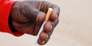 Hand of African man holding a cigarette, emphasising the need for tobacco control