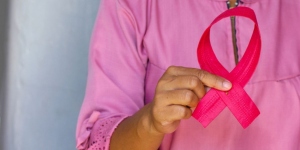 Woman dressed in pink holding a pink ribbon, symbolising breast cancer awareness month
