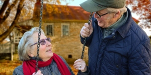 Elderly woman on a swing looking up at an elderly man