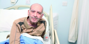 Male patient sitting up in his medical bed at the King Hussein Cancer Foundation in Jordan