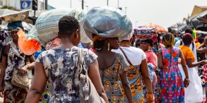 Image from behind of women in Africa walking in a market, some carrying parcels on their heads