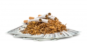 Pile of cut tobacco with cigarettes on dollar bills.