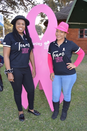 Zambia Cancer Society team members in front of pink ribbon